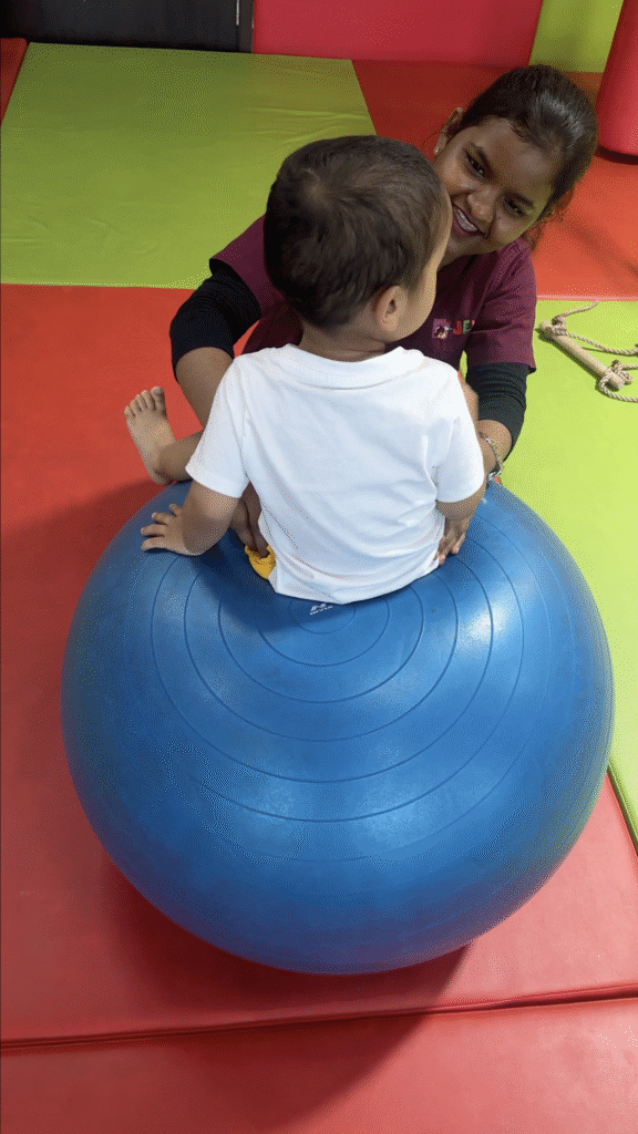 Therapist assisting a young girl with bilateral coordination using sensory balls during an occupational therapy session.